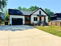 Charming new construction home featuring a black garage door, stylish wood and white siding, and a spacious driveway at 2907 Lake Ave, Charlotte, NC 28208