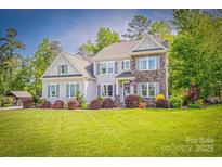 Charming two-story home with stone accents, gray siding, shutters, manicured lawn, and an American flag on display at 3992 Blue Dory Ln, Denver, NC 28037