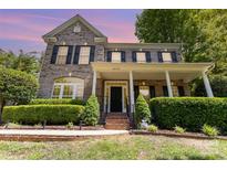 Charming two-story brick home featuring a welcoming front porch and manicured landscaping at 6729 Garden Hill Dr, Huntersville, NC 28078