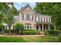Charming two-story brick home with a manicured lawn, black shutters, and a welcoming front porch at 6729 Garden Hill Dr, Huntersville, NC 28078