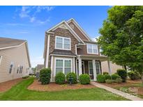 Charming two-story home with a combination of stone and siding, complemented by manicured landscaping and mature trees at 1004 Craven St, Indian Trail, NC 28079