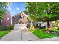 Beautiful two-story home with stone exterior, attached garage, manicured lawn, and mature trees at 10115 Paxton Run Rd, Charlotte, NC 28277