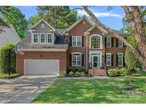 Charming brick home with a well-manicured lawn, attached garage, and mature trees in a peaceful neighborhood at 1400 Coachman Dr, Waxhaw, NC 28173