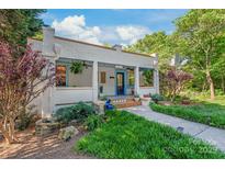 Charming stucco home with a covered porch, blue accents, and beautifully landscaped front yard at 1822 Hall Ave, Charlotte, NC 28205