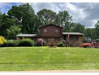 Charming two-story home with brick facade, red shutters, well-manicured lawn and landscaped yard at 204 Aspen Dr, Gastonia, NC 28052