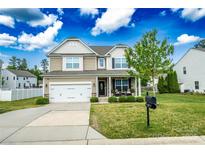 Inviting two-story home featuring a well-manicured lawn, attached two-car garage, and charming front porch at 217 Hydrangea Dr, Clover, SC 29710