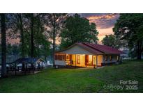 Charming lakeside home with a red roof, screened-in porch, and gazebo, nestled among mature trees under a colorful sunset sky at 4599 B & C Dr, Catawba, NC 28609
