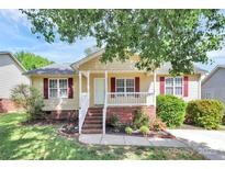 Charming single-story home featuring a welcoming front porch, brick accents, and colorful landscaping at 5114 Daffodil Ln, Concord, NC 28025