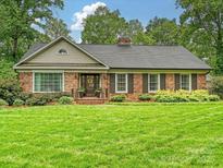 Charming brick home with a manicured front lawn, mature trees, and shutters at 5624 Warewhip Ln, Charlotte, NC 28210