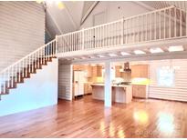 Spacious living room with hardwood floors, white-painted logs, and a kitchen view at 7811 Babe Stillwell Farm Rd, Huntersville, NC 28078