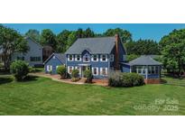 Charming two-story home with blue siding, white trim, brick chimney, and mature landscaping at 106 Chatworth Ln, Mooresville, NC 28117