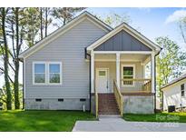 Inviting single-story home featuring a cozy front porch with gray siding and well-manicured lawn at 1101 Kenly St, Salisbury, NC 28144