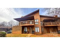 Charming two-story townhouse boasts a wooden exterior, private balcony, and cozy front porch seating at 1832 J Julian Ln, Charlotte, NC 28208