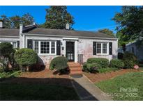 Charming, whitewashed brick home with manicured landscaping, black shutters, and a cozy front porch at 1904 Lynnwood Dr, Charlotte, NC 28209