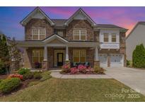 Stately brick home with lush landscaping, a welcoming front porch, and a three-car garage, showcasing curb appeal at 2041 Topaz Plz, Davidson, NC 28036
