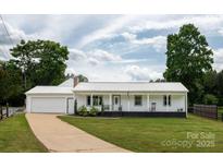 Charming single-story home featuring a white exterior, metal roof, and inviting front porch at 2054 Hickory Hills Dr, Denver, NC 28037
