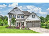 Charming two-story home with manicured lawn, stone accents, three car garage, and covered front porch at 2625 Rea Pond Ct, Charlotte, NC 28226