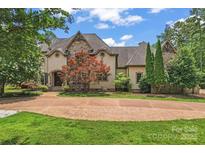 Elegant two-story home featuring a stone and stucco facade, beautiful landscaping, and a winding driveway at 277 Tradition Dr, Mount Gilead, NC 27306
