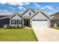 Charming one-story home with a well-manicured lawn, gray siding, a two-car garage and beautiful landscaping at 5112 Larewood Dr, Charlotte, NC 28215