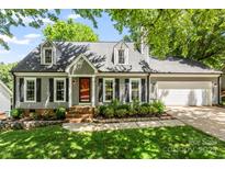 Charming home featuring a well-manicured front yard, gray siding, black shutters, and a red front door at 540 Garrison Sw Ct, Concord, NC 28025