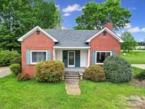 Charming brick home featuring a quaint front porch, light blue shutters, and a well-manicured lawn with lovely landscaping at 5573 Main St, Fort Lawn, SC 29714