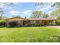 Charming brick home with a well-manicured lawn, mature landscaping, and a convenient carport at 812 Clinton Ave, Lancaster, SC 29720
