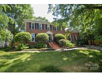 Traditional brick home with a manicured lawn, mature trees and black shutters at 1023 Evian Ln, Matthews, NC 28105