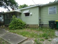 Exterior elevation of light green single Gathering house with overgrown lawn and covered entry and awnings at 1027 Old Plank Rd, Salisbury, NC 28144