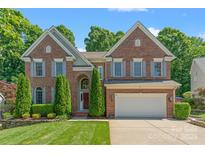 Stately brick home with manicured lawn, mature trees, and two-car garage at 111 Wilton Pl, Mooresville, NC 28117