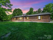 Charming brick home with manicured lawn and lush trees under a colorful sky at 1207 Carlson Dr, Monroe, NC 28110