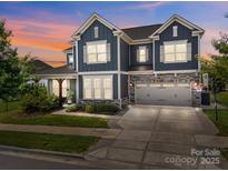 Attractive two-story home features a two-car garage and a well-manicured lawn under a colorful sunset at 17513 Julees Walk Ln, Davidson, NC 28036