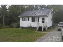 A charming home with white siding, a well-maintained lawn, and a gravel driveway at 201 Trinity St, Clover, SC 29710