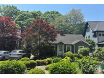 Charming home with a lush, landscaped front yard featuring mature trees and vibrant shrubbery at 2112 Bay St, Charlotte, NC 28205