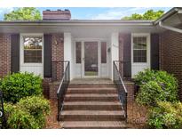 Charming brick home entrance featuring brick steps, black iron railings, and a glass front door with sidelights at 2410 Armstrong Park Dr, Gastonia, NC 28054