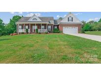 Charming brick home featuring a well-manicured lawn, front porch, and an attached two-car garage at 34843 Ellis Spring Ct, Albemarle, NC 28001