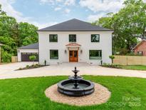 Striking white brick home featuring a water fountain, black trim windows, wooden front door, and well-manicured lawn at 3501 Providence Rd, Charlotte, NC 28211