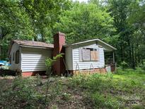Exterior view of a white house with a brick chimney surrounded by lush green trees at 455 Running Brook Rd, Midland, NC 28107