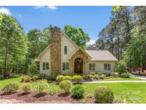 Charming home with a stone chimney, arched entryway, and manicured landscaping at 6599 Majestic Pine Dr, Vale, NC 28168