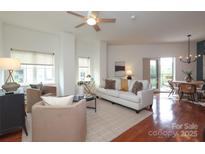 Bright living room featuring a ceiling fan, hardwood floors, a white sofa, balcony access, and large windows at 721 Governor Morrison St # 520, Charlotte, NC 28211