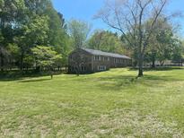 Expansive lawn and mature trees surround this brick home with bright, white-trimmed windows at 205 Rudolph Rd, Salisbury, NC 28146