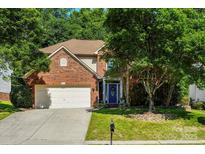 Charming two-story brick home with lush green lawn, mature trees, and a two car garage at 5818 Downfield Wood Dr, Charlotte, NC 28269