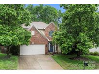 Charming brick two-story home featuring a two-car garage and mature trees at 5818 Downfield Wood Dr, Charlotte, NC 28269