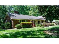Charming single-story brick home with a lush green lawn, mature trees, and vibrant landscaping at 701 5Th Ne Ave, Conover, NC 28613