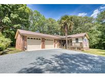 Charming home featuring a two-car garage, front porch, and a spacious driveway surrounded by mature trees at 3116 Old Montgomery Place Rd, Monroe, NC 28112