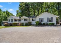 Charming single-story home with a covered porch, black shutters, mature trees and an expansive paved driveway at 370 Shiloh Rd, Statesville, NC 28677