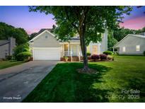 Charming home featuring a manicured lawn, two-car garage, and inviting front porch at twilight at 374 Queens Sw Dr, Concord, NC 28025