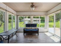 Inviting sunroom featuring wood floors, ample natural light, and comfortable wicker seating with views of the backyard at 374 Queens Sw Dr, Concord, NC 28025