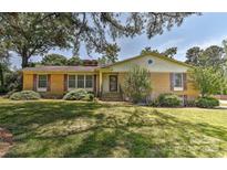 Charming brick home featuring a well-maintained lawn, mature trees, and a welcoming entrance at 385 Gum Branch Rd, Charlotte, NC 28214