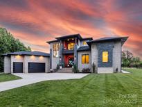 Stunning modern home featuring a two-car garage, well-manicured lawn, and elegant architectural design under an orange sunset at 4315 Hartis Grove Church Rd, Indian Trail, NC 28079