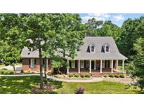 Charming brick home with a welcoming front porch, beautiful landscaping, and mature trees on a well-manicured lawn at 4570 Chanel Ct, Concord, NC 28025